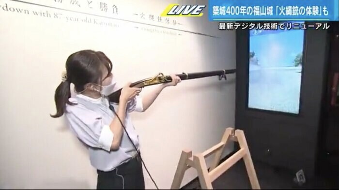デジタル映像の的めがけて火縄銃を構える中西アナ