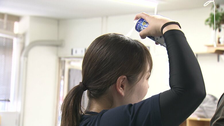 ヘルメットをかぶる前、冷感スプレーで頭部を冷やす