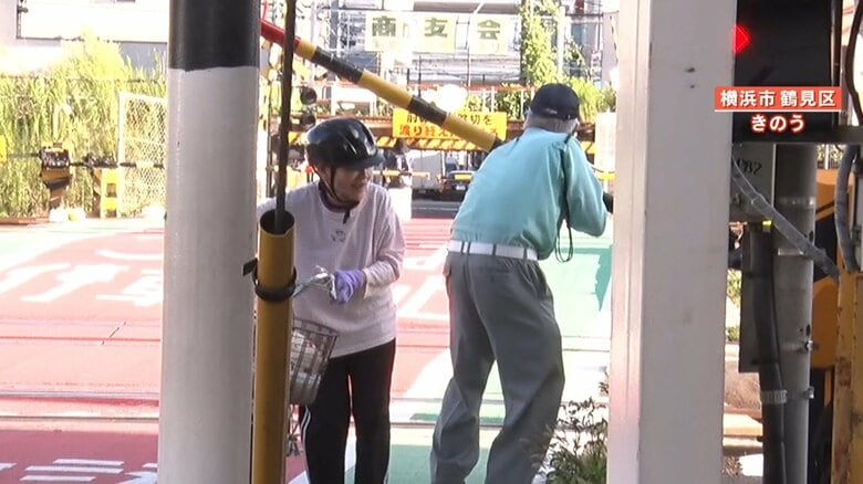 渡りきれない人のために、警備員が手でバーを上げる