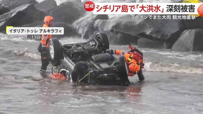 海に漬かった状態で横転する車 その近くでは、救助隊員が中に人がいないかなどを確認している様子が