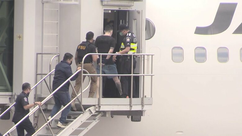 日本に向かう航空機に乗せられる藤田聖也容疑者