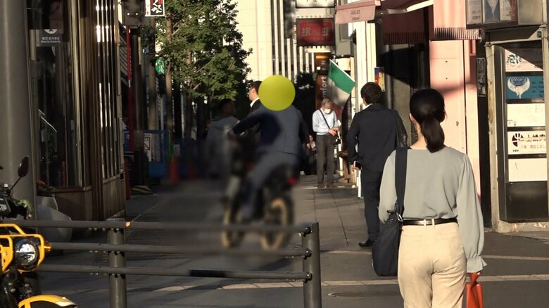 歩行者の間をすり抜けながら、歩道を走るフル電動自転車