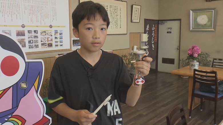 山本おたふく堂の「ふろしきまんじゅう」グッズを手にする羽原瑠良くん
