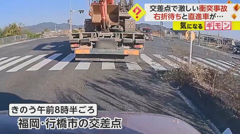 右折待ちをしている重機を載せたトラック