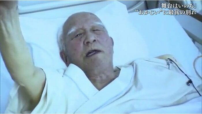 病室で拳を高く突き上げる岡田忠雄さん