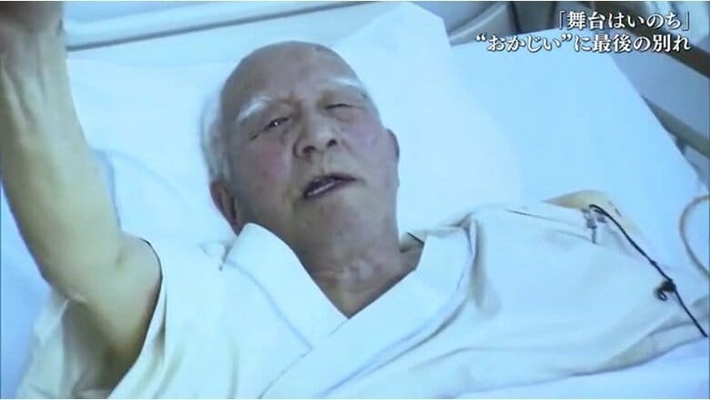 病室で拳を高く突き上げる岡田忠雄さん